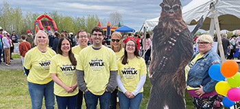 Group of People Standing Next to Chewbacca Cutout