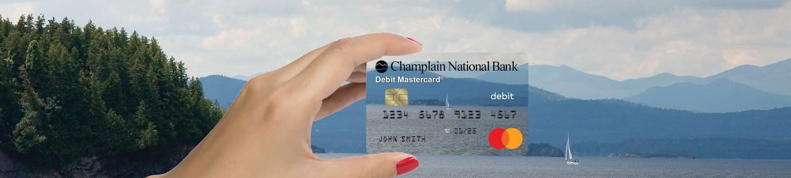 Hand holding a Debit Card Over a Sky, Mountain, Lake scene