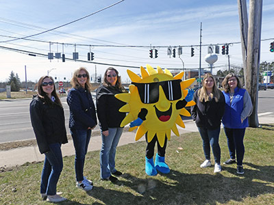 Five People Standing Next to a Sun Costume