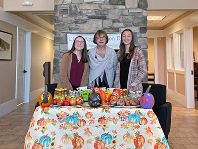 Three Girls Standing Behind Decorated Table with Halloween Decorations and Treats