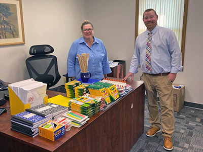School Supplies Neatly Arranged on a Desk, with Kelly and Wade Standing Next to it