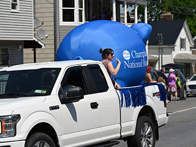 Girl waving to parade goes from the cab of a pickup truck