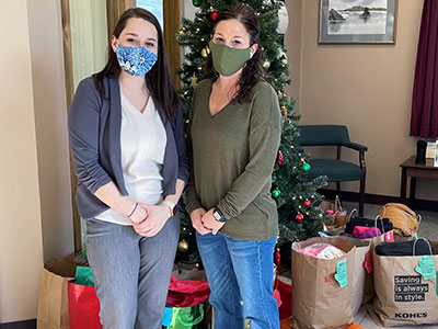 Kelsey and Michelle standing in front of Christmas Tree with Gifts Underneath
