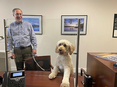 Man Holding Leash Attached to Dog with Paws on Desk