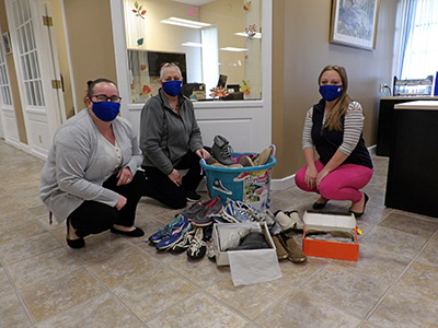 Lisa, Lena, and Tiffani bending down next to a pile of sneakers and shoes