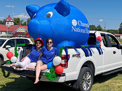 Two Girls Sitting in the Cab of a Truck with a large inflatable piggy bank
