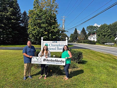 Three People Standing in front of Champlain National Bank Sign