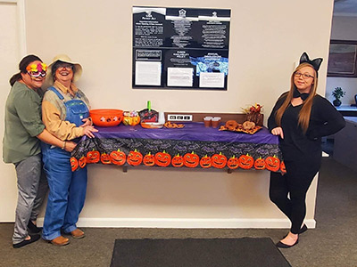 Three Girls Wearing Halloween Costumes Next to a Table Decorated for Halloween