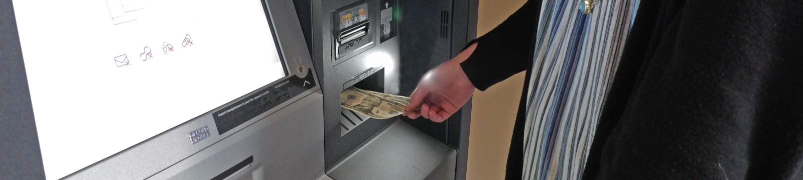 Person Inserting Cash Into an ATM
