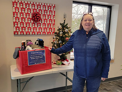 Woman Standing Next to a Box Full of Warm Clothing