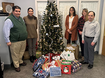 Four People Standing Next to a Christmas Tree with Wrapped Christmas Presents