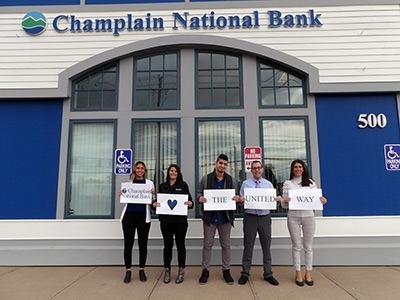 Five People Holding a Sign that Says Champlain National Bank Loves the United Way