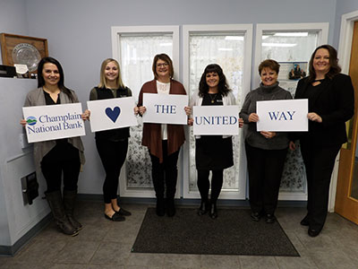Women Holding Signs that Spell Out Champlain National Bank Loves The United Way